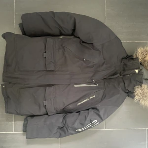 Svart dunjacka Peak Performance M - Svart dunjacka från Peak Performance med avtagbar huva och flera fickor och dragkedjor. Jackan har broderad logga på bröstet och är fodrad för extra värme. Perfekt för kalla vinterdagar!! Den är ren, bra skick och säljer pga kommer inte till användning, pris kan diskuteras!🥰