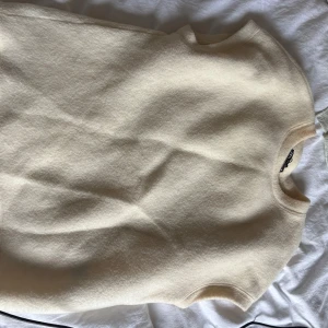 Beige tröja från Zara - Supermjuk och stilren beige tröja från Zara i ärmlös modell. Tröjan har rund halsringning och är gjord i ett fluffigt, stickat material som känns både trendigt och bekvämt. Perfekt att styla med skjorta under eller som den är.