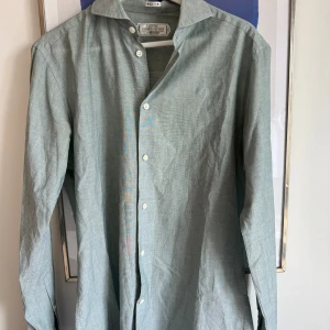 Ljusgrön skjorta från These Glory Days - Snygg ljusgrön skjorta från These Glory Days i slim fit-modell. Skjortan har klassisk krage, vita knappar och är tillverkad i ett tunt bomullstyg. Perfekt för dig som gillar stilrena och enkla plagg med skandinavisk känsla.