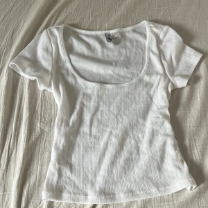 Vit topp från H&M Divided - Vit topp från H&M Divided med kort ärm och urringning. Tunt, stretchigt bomullsmaterial med mönster i tyget. Väldigt gullig💕💕 kontakta för fler frågor