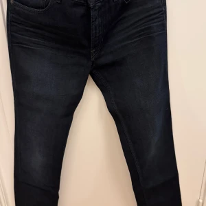 Mörkblå jeans från Acne - Snygga mörkblå Acne jeans med klassisk femficksdesign och smal passform. Jeansen har en stilren look med lätt tvättade detaljer och är tillverkade i mjukt denimtyg. Perfekta för dig som gillar en modern och clean stil. Som nya. Storlek 31/32.