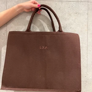 Brun stor väska från LXA - Brun stor väska från Linn ahlborgs märke LXA. Super fin men nästintill oanvänd! Lite toteväska liknande. Mått: Längd 45, Höjd 35cm, Bredd 16cm