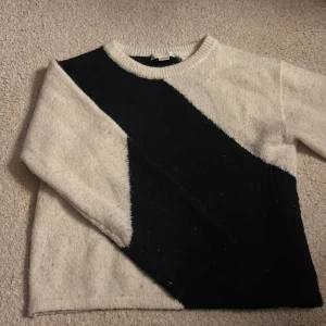 Svartvit stickad tröja Gina Tricot - Säljer en stickad tröja från Gina Tricot i svart och vitt med ett coolt diagonalt blockmönster. Tröjan har rund halsringning och långa ärmar, perfekt för att hålla sig varm och snygg under kyliga dagar.