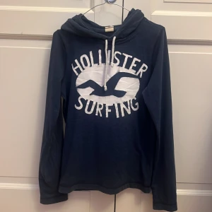 Hollister Surfing hoodie - Hollister hoodie i ny skick använd ett fåtal gånger. Storlek S passar någon runt 170.