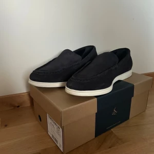 Svarta mockaloafers från Charles Tyrwhitt - Stilrena mörkblåa loafers i mocka från Charles Tyrwhitt med vit platt sula. Skorna har klassisk design med rund tå och är perfekta för en clean och avslappnad look. Passar till både jeans och chinos för en snygg vardagsstil. Vanligt pris är 1300!