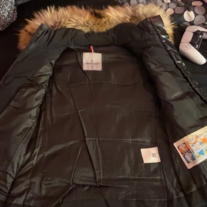 Svart Monclerväst med päls - Svart monclerväst med päls runt luvan. Storleken M men den är väldigt liten i midijan XS