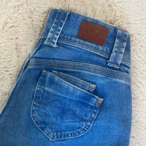 Blå straight jeans från Pepe Jeans - Snygga blå jeans från Pepe Jeans med raka ben och låg midja.  dubbla knappar i midjan och detaljerade sömmar. Jeansen är tillverkade i denim och har en stilren look med Pepe Jeans-logga på bakfickan och läderpatch bak, skriv för frågor ❣️
