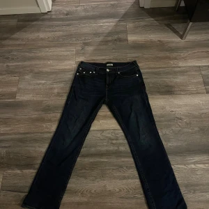 Mörkblå jeans från True Religion - Snygga mörkblå jeans från True Religion med klassiska kontrastsömmar och ikoniska bakfickor med lock och silverfärgade knappar. Jeansen har rak passform och normal midja, tillverkade i slitstarkt denim. Perfekta för dig som gillar streetwear och detaljer.