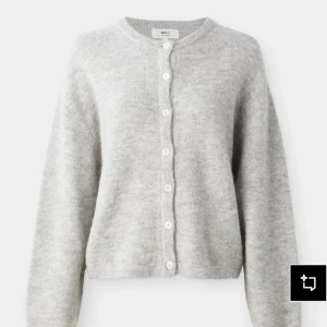 Grå kofta från Gina Tricot - Mysig grå kofta från Gina Tricot med rund halsringning och knappar framtill. Koftan är stickad och har en lite loose passform med långa ärmar. Perfekt att slänga på sig när det är kyligt ute. Knappan längst upp har åkt av men det finns en påse med någon knapp i som lätt går att sy på igen . Prislappen är kvar 