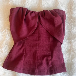 Vinröd tubtopp från Zara - Supersnygg vinröd tubtopp från Zara. Toppen är axelbandslös och har en figurnära passform som framhäver siluetten. Perfekt för hösten❤️