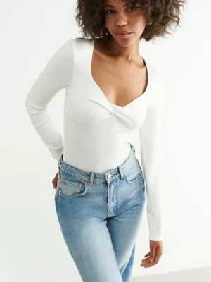 Vit långärmad topp från Gina Tricot - Säljer en vit långärmad topp från Gina Tricot i storlek XXS. Toppen har en snygg v-ringning med twistad detalj framtill och är figurnära i modellen. Perfekt att styla med jeans eller kjol för en clean look.