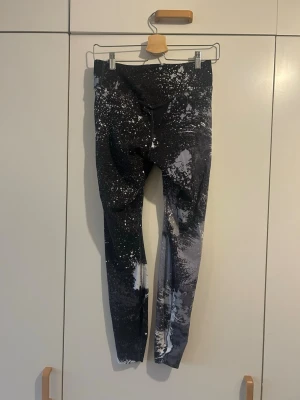 Nike leggings - Snygga Nike Dri-Fit leggings i svart och grått med coolt splash-mönster i vitt. De är tighta och har en hög midja som sitter skönt vid träning. 