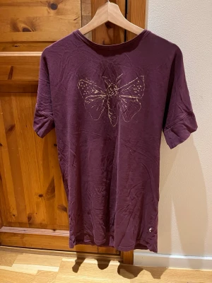 Nattlinne/klänning - Skönt nattlinne i storlek 146/152 från POMPdeLUX. Bra skick, trycket på magen kan upplevas något slitet men inget som jag tycker påverkar helhets intrycket av linnet. Kan givetvis användas som vanlig klänning eller vad man nu känner för! Har själv använt det som nattlinne och den var väldigt skön att sova i. Färgen skulle jag säga är lila, Burgundy eller vinröd med lila toner i.Säljes då den är för liten i storlek. Djur och rökfritt hem.