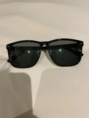 Raybans solglasögon 2428 - Säljer dessa riktigt snygga svarta raybans. Linsen är i färg grön/blå och den är i mycket bra skick, inga repor. Finns ingen box.