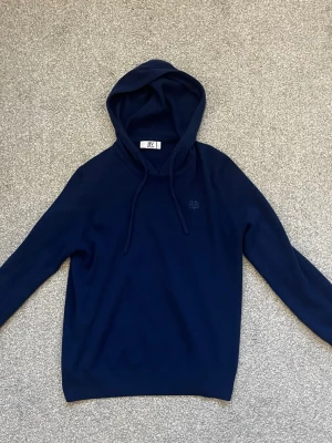 Marin blå Bvaldi hoodie (Lusso Morbido cashmere)) - Marin blå hoodie från Bvaldi, säljer pågrund av att den är förliten. Hoodie sitter bra om du är cirka 165. Tröjan är lite sönder vid kragen som man kan se på andra bilden. Skriv vid minst fundering! 