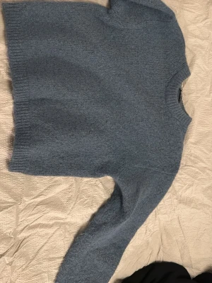 Blå stickad tröja - Mysig blå stickad tröja med rund halsringning och långa ärmar. Tröjan har en enkel, clean look. Perfekt för kyliga dagar och enkel att matcha med jeans eller kjol.