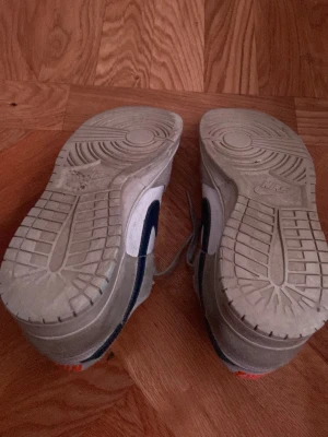 Nike Dunk Low i beige och vitt - Nike Dunk Low sneakers i grå mocka, ganska väl använda och smutsiga, samt slit på sulan samt vid hälen, men överlag i ganska bra skick