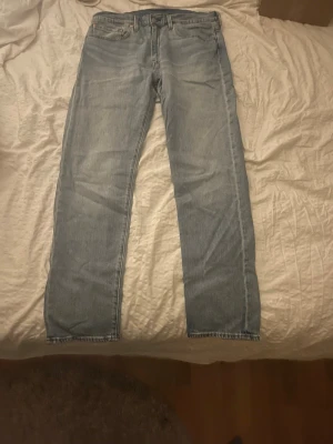 Levi's ljusblå jeans - Ljusblå Levi's 502 jeans med klassisk femficksdesign och raka ben. Jeansen har en snygg tvättad look, normal passform och är tillverkade i slitstarkt denim. Perfekta för dig som gillar en tidlös och clean stil. Midjan är normal och materialet är 100% bomull. Nypris 1200kr mycket bra skick använda ett fåtal gånger. Midjelängd ungefär 45cm benlängd ungefär 80cm