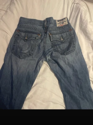 Baggy true religion jeans - använder mina bilder från vinted!! Säljer ett par väldigt baggy true religion jeans som jag säljer då de inte kommer till användning så ofta. Har snygga hål på framsidan och är väldigt sköna att ha på sig. Jeansen är för långa för mig som är 162 och har därför fått heelbites på båda benen. Perfekta för dig som vill ha en baggy passform på dina jeans!! Hör av er angående frågor eller fler bilder och vänligen hör av er innan köp☺️