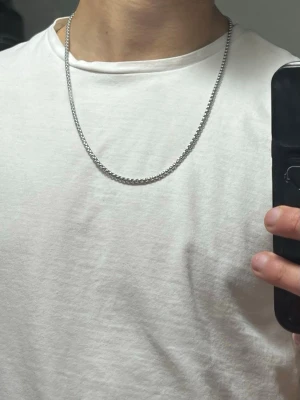 Silverfärgad boxkedja halsband 60cm cm - Säljer ett stilrent halsband med boxkedja i silverfärg. Kedjan är ca 60 cm lång och har ett klassiskt lås. Perfekt för dig som gillar minimalistiska smycken med lite edge. Passar till allt!