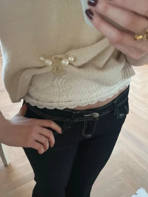 Vit spetsblus med spets  - Säljer en söt vit blus i spets med fina volangdetaljer vid axlarna och runt halsen. Blusen är ärmlös och har ett romantiskt mönster med blommor i spetsen. Perfekt att styla med jeans eller kjol för en fräsch look.