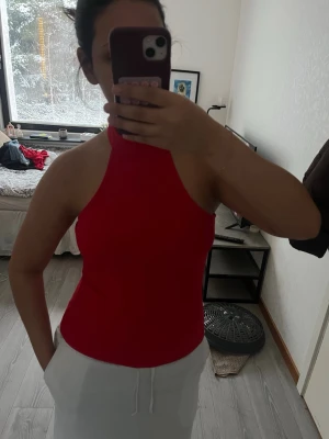 Röd halterneck linnetopp från NA-KD - Säljer en snygg röd halterneck topp från NA-KD i storlek S. Toppen är ärmlös och har en tight passform med hög hals. Perfekt för sommardagar eller när du vill ha en enkel men stilren look. Materialet är mjukt och stretchigt för en bekväm känsla. En knapp har gått av (bild 3) men fungerar fortfarande lika bra att knäppa. 