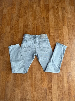 Slim jeans Jack & Jones - Säljer ett par ljusgrå skinny jeans från Jack & Jones i storlek 29/30. Jeansen har klassisk femficksdesign, smal passform och är tillverkade i stretchig bomullsdenim för extra komfort. Perfekta för dig som gillar en modern och clean look.