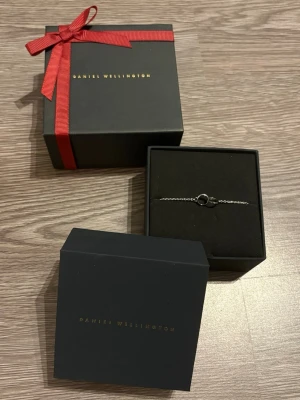 Daniel Wellington armband - Helt ny Daniel Wellington armband i silver. Väldigt subtil detalj med texten ”Daniel Wellington” på ringarna. Armbandet är 15cm lång. Lådorna medföljes men kvittot saknas då det är en present. 