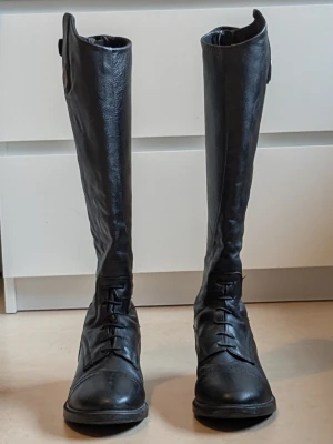Ridstövlar CRW i skinn, 38 - Höga svarta ridstövlar i äkta skinn från CRW. Perfekta för dig som vill ha stilrena och funktionella ridstövlar till ridning. Två små defekter på utsidan av ridstövlarna, visas på bifogade bilder