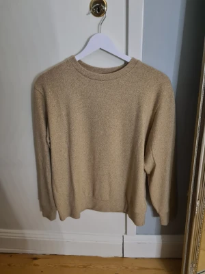 Beige stickad tröja  XS - Säljer en enkel och stilren beige stickad tröja från Uniqlo i storlek XS. Tröjan har rund hals, långärmad design och mjukt material som känns skönt mot huden. Perfekt för lager-på-lager och chill dagar. Färgen är neutral och passar till det mesta.