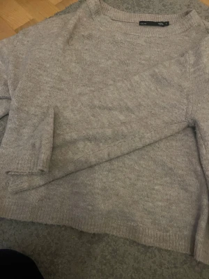 Beige stickad tröja från 157 - Mysig beige stickad tröja från 157 i storlek S. Tröjan har rund hals och långa ärmar med ribbade muddar vid ärmslut och nederkant. Perfekt för lager-på-lager under kyliga dagar och enkel att matcha med jeans eller kjol.