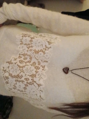 Vit stickad tröja med spetsdetalj - Mysig vit stickad tröja med lång ärm och bred spetsdetalj i blommigt mönster framtill. Perfekt för dig som gillar romantiska detaljer och vill ha något extra till garderoben.