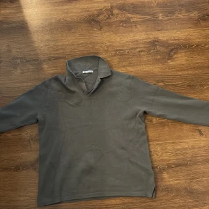 Grå fleece polotröja från Zara - Mysig grå polotröja från Zara i fleece med hög krage och knappar vid halsen. Tröjan har lång ärm och en loose passform, perfekt för kyliga dagar. Enkel och stilren design som funkar till många outfits.