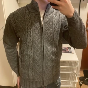 Stickad kofta med mönster - Riktigt fin grå stickad kofta med mönster. Otroligt skönt material innuti . Storlek M men passar även S. Modellen är 180cm, 73kg. Priset kan diskuteras.