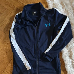 Under Armour Tröja - Säljer för den blivit för lite i armarna och längd, tröjan har varit med om en olycka men har fixats, syns inte alls när du har på dig tröjan. Tröjan har även ett litet hål på magen men ej stort. Hör av dig om det något annat du vill veta, Mvh 