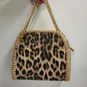 Leopardmönstrad handväska med kedja - Snygg handväska med leopardmönster och guldfärgad kedja som handtag. Väskan har beige kant med dekorativ snörning och dragkedja på sidan. Perfekt för dig som vill sticka ut med ett djuriskt print och coola detaljer.