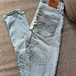 Levi's 710 Super Skinny ljusblå jeans - Säljer ett par Levi's 710 Super Skinny jeans i ljusblå tvätt. De har klassisk femficksdesign, Levi's logga på bakfickan och är tillverkade i stretchigt jeansmaterial för en tight passform. Perfekta om du gillar en smal siluett och vill ha ett par riktigt snygga jeans.