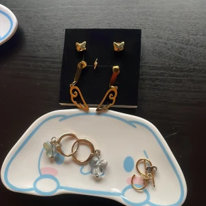 Guldörhängen i olika format - Vingarna- lite smårepor men som knappts syns - 50kr.  Glitter Guldringar i äkta platterat guld 60kr (dock ena ploppen som försvunnit ersätter med en kopparplopp) UO Fjärilsörhängen, inte bästa kvale och på ena örhänget är ögglan lite sne vilket gör så fjärilen sitter lite sne(kan fixas med tång själv) 30kr.     Edblad Allergifria Fjärilsörhängen i Kids Size (funkar för vuxna också bara mindre i strl) 80kr                                   Lilla blixten utan plopp 15kr äkta platterat guld.    