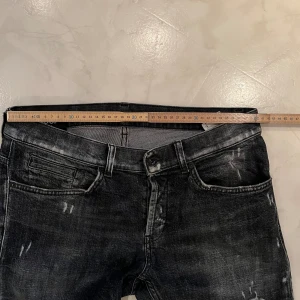 Svarta skinny jeans från George - Säljer ett par svarta skinny jeans från George med slitna detaljer och tvättad look. Jeansen har klassisk femficksdesign, knapp och dragkedja framtill samt smal passform hela vägen ner. Perfekt för dig som gillar en edgy stil.