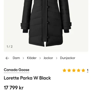 Svart dunjacka Canada Goose Lorette - Säljer en svart Lorette Parka från Canada Goose med klassisk patch på ärmen och snygg pälskantad huva. Jackan är lång, har dragkedja och knappar framtill samt quiltad design. Perfekt för kalla vinterdagar och riktigt varm.