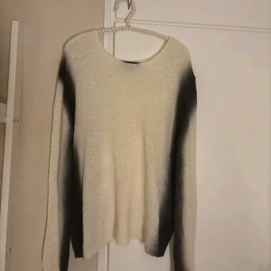 Vit och svart stickad tröja från Zara - Säljer en stickad tröja från Zara i storlek S. Tröjan är vit/begie med svarta, mjuka övergångar längs ärmarna och axlarna. Den har rund hals och långärmad passform, perfekt för dig som gillar en chill och stilren look.