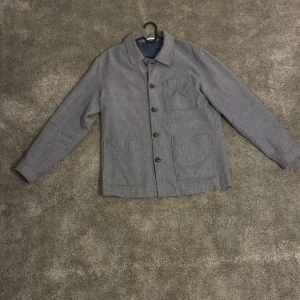 Rutig overshirt från Jack & Jones L - Snygg rutig overshirt från Jack & Jones i blå och grå toner. Jackan har klassisk krage, knäppning framtill, tre fickor och långa ärmar med knapp vid ärmslut. Slim fit-modell i ett lätt bomullsmaterial, perfekt för lager-på-lager.