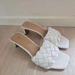Vita flätade sandaler med klack från H&M - Högst bud 77kr  Helt nya, passar även 37. Säljer ett par vita sandaler från H&M med låg klack och fyrkantig tå. Ovandelen har en snygg flätad design i syntetmaterial som ger en trendig look. Perfekta för sommarens alla tillfällen och passar dig som gillar stilrena detaljer.
