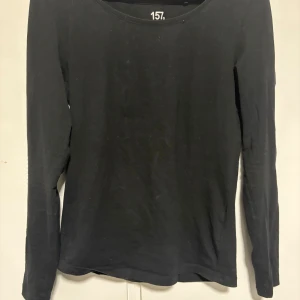 Svart långärmad tröja från 157 - En enkel svart långärmad tröja från 157 i storlek S. Tillverkad i mjuk bomull med lite stretch för skön passform. Perfekt att ha som basplagg och funkar till alla dina favoritoutfits. Rund halsringning och stilren design. (Använt några få gånger).