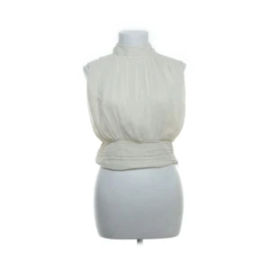 Vit plisserad blus från Zara - Säljer en snygg vit blus från Zara med plisserat tyg och hög hals. Blusen är ärmlös och har en bred, markerad midja som ger en cool siluett. Perfekt för dig som gillar stilrena och trendiga plagg. För liten för mig så kan tyvärr ej visa på❤️