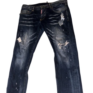 Mörkblå  DSQ2 jeans - Snygga mörkblå jeans från One Life med slitna detaljer och patchar på framsidan. Jeansen har raka ben och klassisk femficksdesign. Perfekt för dig som gillar en lite ruffare streetstil. Materialet är robust denim i bomull.