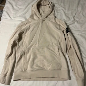 Beige hoodie från Calvin Klein Jeans - Snygg beige hoodie från Calvin Klein Jeans med klassisk CK-logga på ärmen. Tröjan har huva, magficka och ribbade muddar vid ärmslut och nederkant. Perfekt för chill dagar och enkel att matcha med jeans eller joggers.