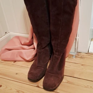 Bruna mockastövlar med klack - Snygga bruna stövlar i mjuk mocka med rund tå och hög klack. Stövlarna har dragkedja på insidan för enkel på- och avtagning. Perfekt för dig som gillar klassisk stil med en twist. Passar till både jeans och kjol.Så snygga vintage mocka stövlar i fint skick. Storlek 38 med lite smalare fot. Nyköpta men passade tyvärr ej mig 🌺