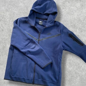 Nike Tech mörkblå - Autentisk Mörkblå Nike Tech. (68cm lång och 57cm bred) Tillverkad i 66% bomull. Snygg och bekväm.🤩 Några mindre tecken på användning. Kontakta gärna för frågor🙌📲
