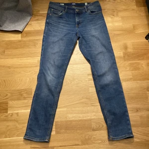 Blå slim jeans från Jack & Jones - Säljer ett par klassiska blå jeans från Jack & Jones i modellen Slim Glenn. Knappast använda lappen bak är lite sönder. Kan diskutera pris